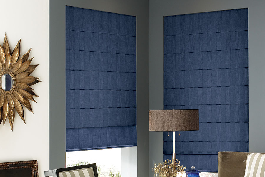Navy blue Roman shades in a corner of a modernly decorated living room.