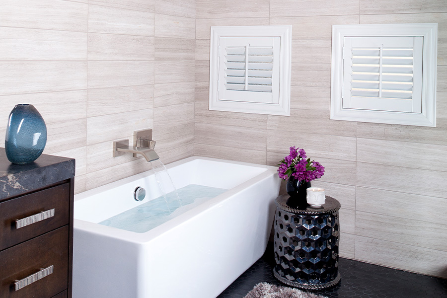 Two casement windows covered by plantation shutters in bathroom.