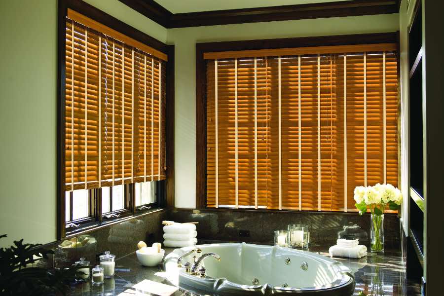 Premium quality blinds are always a stylish accent in your Jacksonville home. Brown wood blinds on large windows in a green bathroom