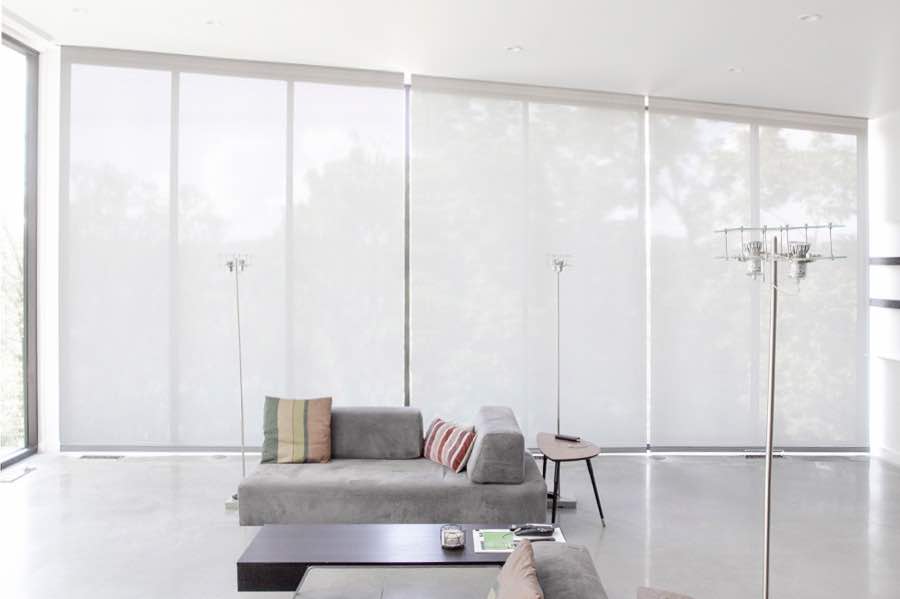Motorized window shades make controlling natural light effortless in your Jacksonville great room. White motorized shades on a wall of tall great room windows
