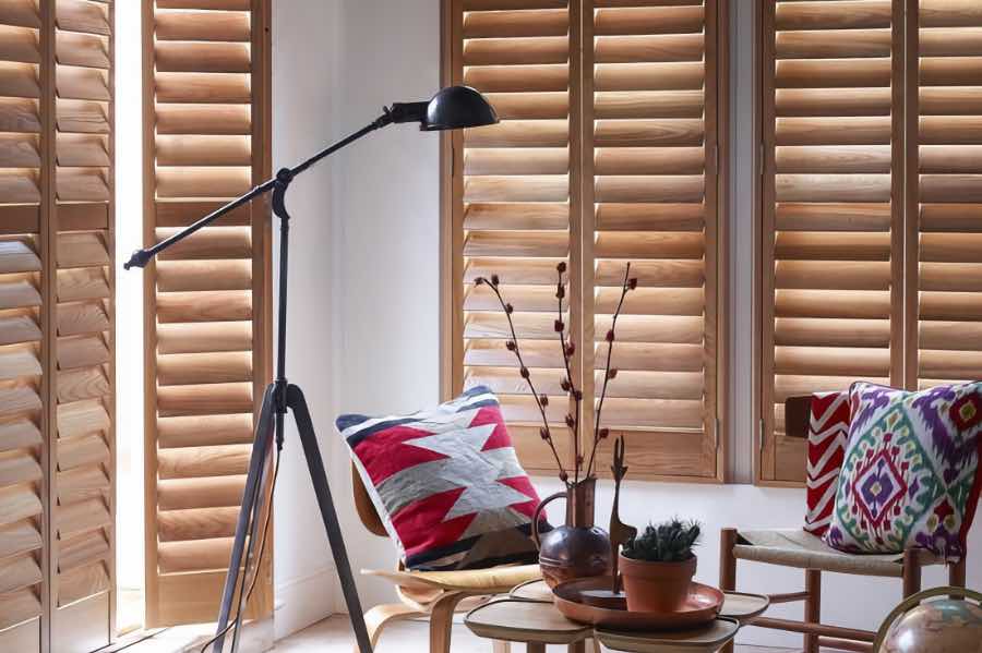 Premium wood shutters are built to last longer than many other window treatments. Brown wood shutters on a living room door and window