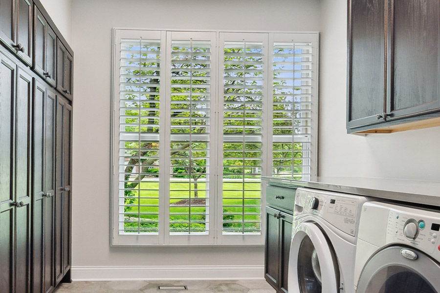 Find the perfect level of natural light for your Jacksonville laundry room with interior shutters. White Polywood shutters letting light through a laundry room window
