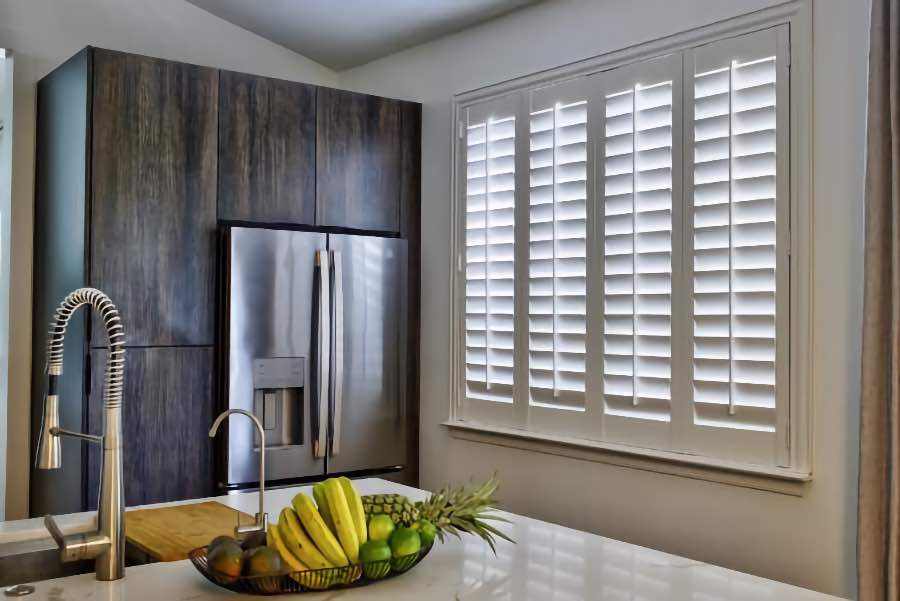 Homeowners use indoor window shutters in Jacksonville when they want attractive and functional window treatments. Polywood shutters on a large kitchen window