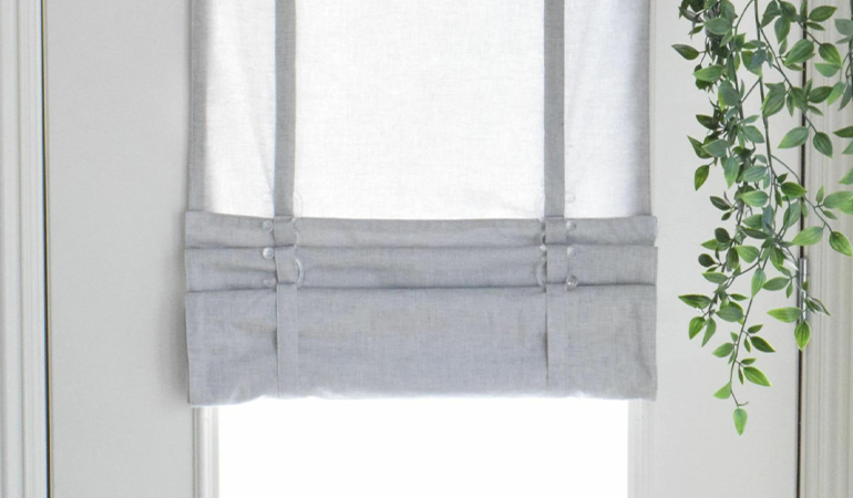 With a tiered tumble shade in Jacksonville, you can block sun glare all year round. Gray rolled tumble shade on a glass door